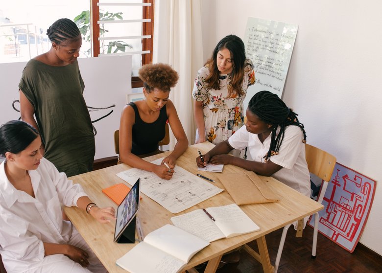 Cinq femmes assises autour d'une table travaillent ensemble