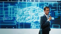 Homme faisant une présentation, cerveau projeté derrière lui sur un écran